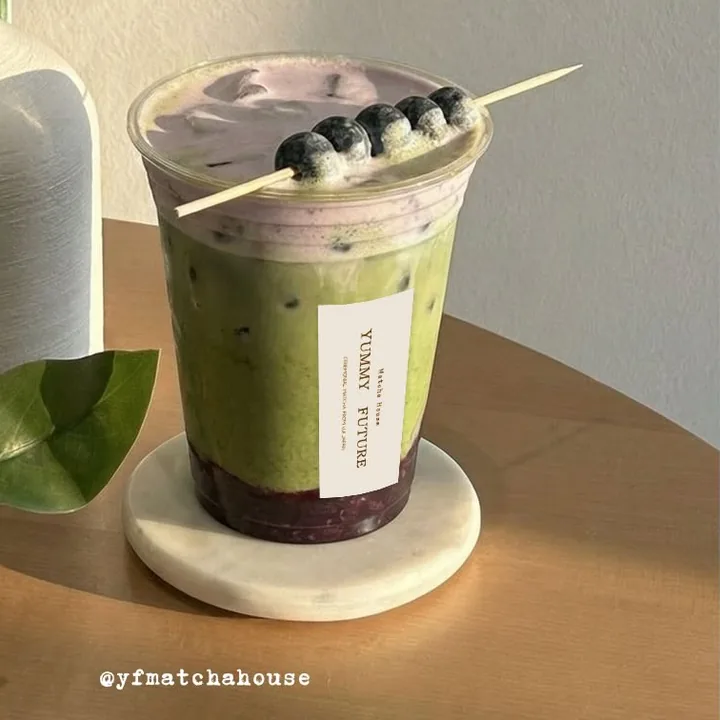 Triple Blueberry Matcha on a marble coaster with a blueberry skewer across the top