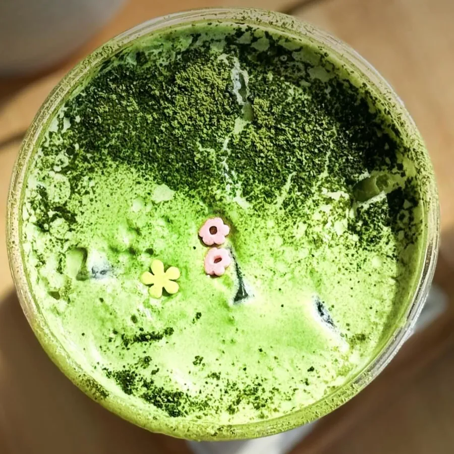 Strawberry Matcha Duo from above: matcha powder dusted over matcha cream, with small candy flowers