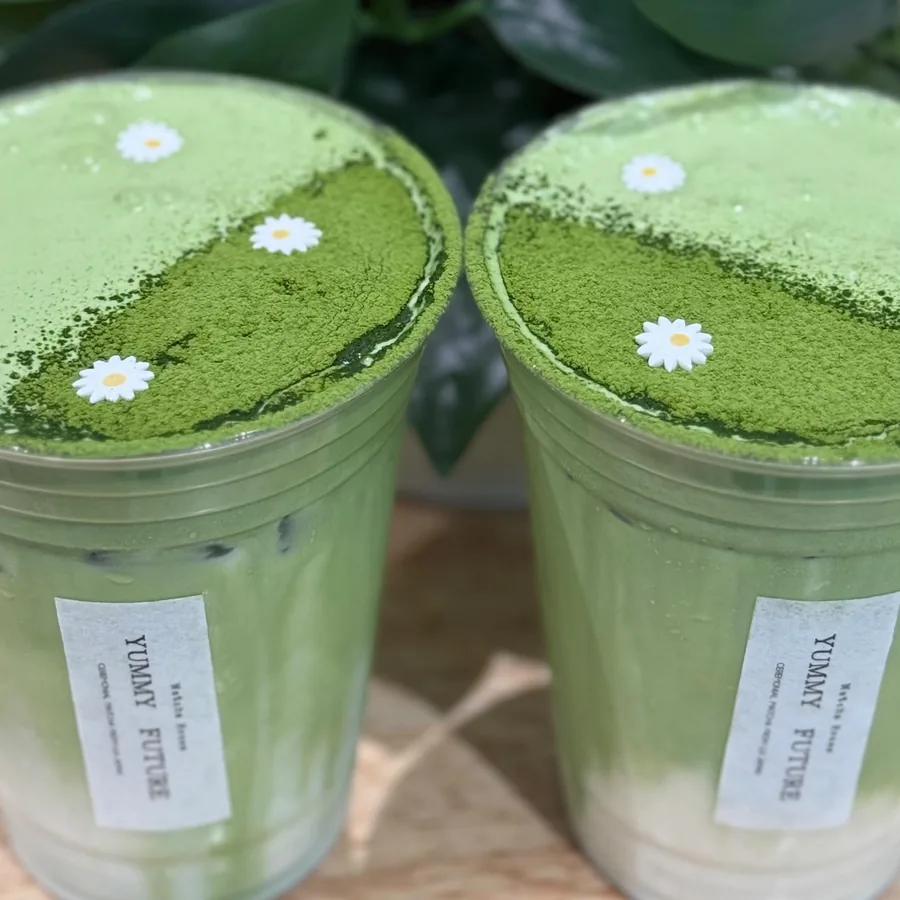 Two iced matcha lattes with daisies on top